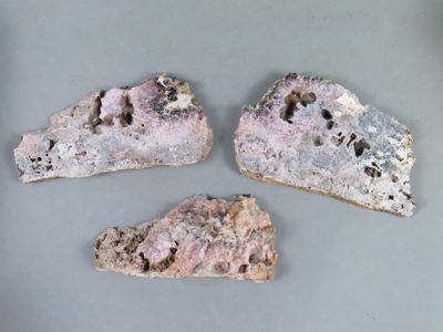trois morceaux de roche percés de trous, posés sur une table