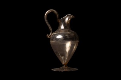 un vase en argent muni d'une anse, sur fond noir