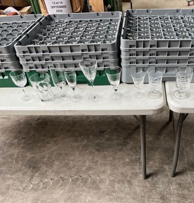Plusieurs verres à vin vides sont posés sur une table dans un entrepôt.