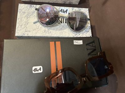 une paire de lunettes de soleil posée sur une boîte à côté d'une autre paire de lunettes de soleil