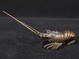 un gros plan d'un objet métallique représentant un homard posé sur une surface noire
