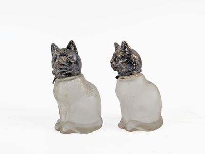 two glass cats sitting next to each other on a white surface