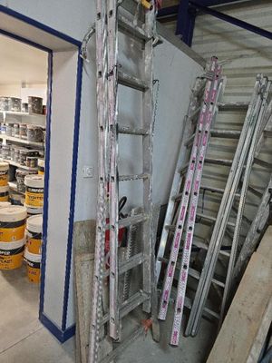 une pièce avec une échelle et plusieurs seaux de peinture par terre