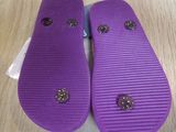 purple flip flops with gold studs on them on a wooden floor
