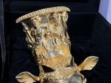 a gold vase that is sitting in a black box