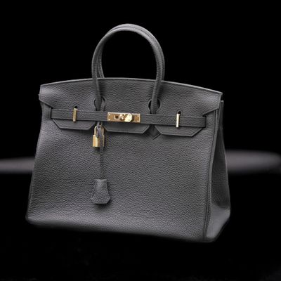a black leather handbag with gold hardware on a black background