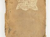 an old book with writing on it sitting on a white surface