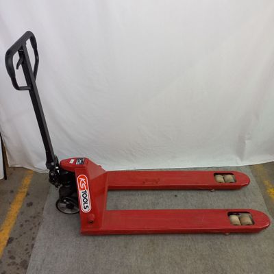 un chariot élévateur rouge posé à même le sol dans un entrepôt