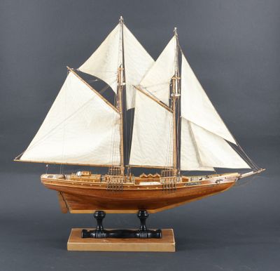 maquette en bois d'un voilier aux voiles blanches, posée sur un socle