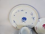 a white table topped with a blue and red plate and a cup and saucer
