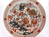 une assiette rouge et blanche décorée d'un oiseau et de fleurs