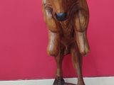 statue of a bull with horns on a wooden base against a red wall