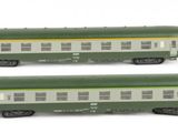 six green and white train cars sitting on top of a white surface