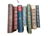 plusieurs vieux livres sont alignés sur une surface blanche