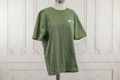 the green t - shirt is on a mannequin stand in front of a white wall