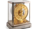 a gold clock inside of a glass case on a white surface