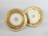 deux assiettes ornées de fleurs dorées et roses sur un fond blanc
