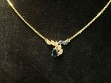 a gold necklace with a blue stone on a mannequin neck