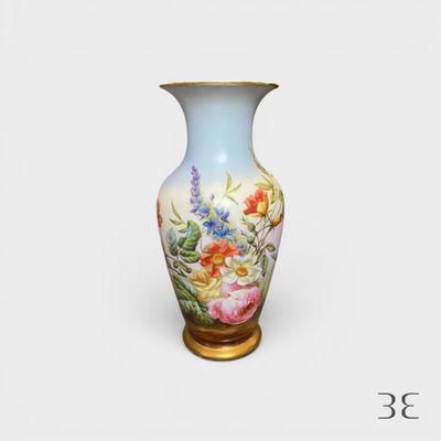 un vase avec des fleurs peintes dessus, posé sur une table