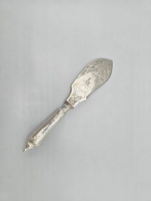 une vieille cuillère en argent avec un manche, posée sur une surface blanche
