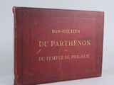 un vieux livre rouge orné de lettres dorées, posé sur une surface blanche