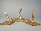 three gold plated candlesticks on stands on a gray surface
