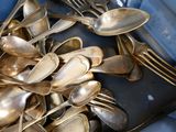 a lot of silver spoons and forks in a blue container