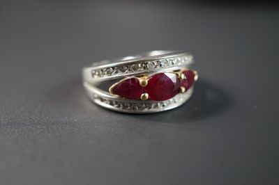 une bague en argent ornée de pierres rouges et de diamants, posée sur une table