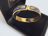 bracelet présenté dans un coffret noir, orné d'une bande dorée et d'un motif bleu et vert