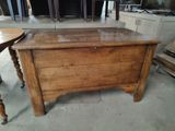a wooden chest on the floor next to a table and chairs