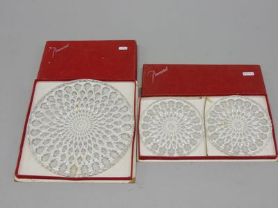 deux dessous de verre blancs en dentelle dans une boîte rouge posée sur une table