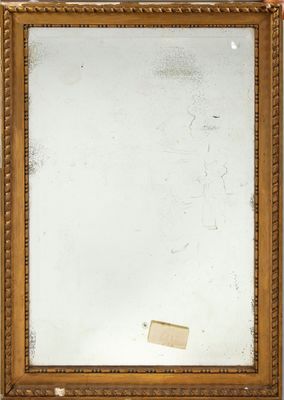 un miroir ancien dans un cadre doré, accroché à un mur blanc, avec un bout de papier
