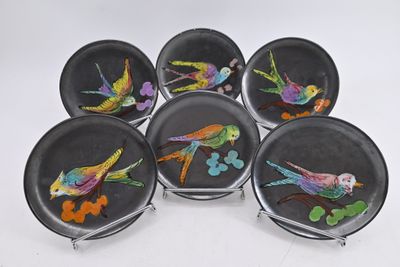six black plates with colorful birds painted on them sitting on a table