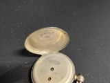 a silver pocket watch sitting on a black surface