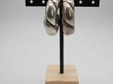 a close up of a pair of silver earrings on a wooden stand