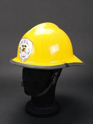 un casque de pompier jaune posé sur une tête de mannequin noire