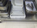 Plusieurs plateaux de nourriture sont empilés sur une étagère métallique dans une cuisine