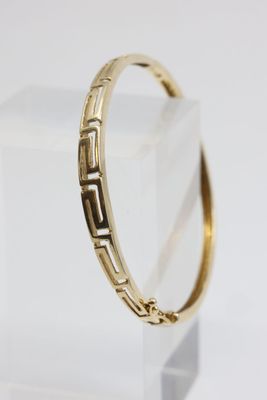 un gros plan d'un bracelet en or posé sur une surface transparente