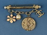 a close up of a brooch with a coin and charms on it