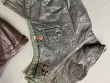 two leather jackets and a hat on a white surface