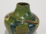 a green vase with a design on it on a white surface