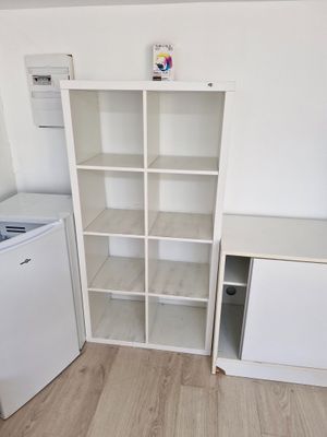 une petite cuisine avec un réfrigérateur blanc et une bibliothèque blanche