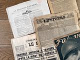 plusieurs vieux journaux posés sur une table en bois, sur laquelle se trouve une photo en noir et blanc d'un homme en uniforme militaire