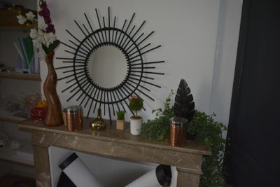 a mirror on the wall above a fireplace with a vase of flowers