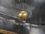 a close up of a leather hat with a gold button on it