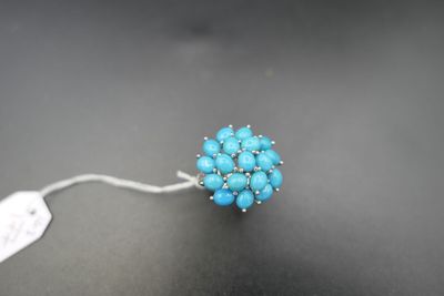 un gros plan d'une bague ornée de perles bleues sur une surface noire