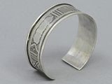 a close up of a silver bracelet with a design on it