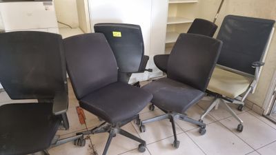 Quatre chaises de bureau sont alignées en rang dans une pièce