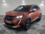 Le SUV orange est garé dans une grande pièce au sol carrelé.