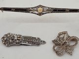trois bijoux argentés et noirs posés sur une surface blanche